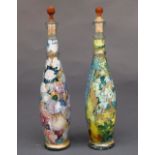 A pair of decoupage style bottles, with stoppers, the club form body with flowerhead and leaf