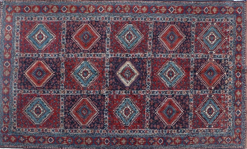 A hand woven Caucasian carpet, the rouge and indigo panelled field with alternating red and blue