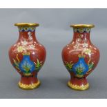 A pair of squat form cloisonne vases, the brick red ground with flowering vase decorated centre.