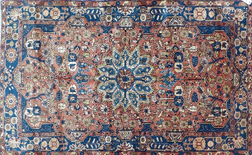 A hand woven Nahavand Persian rug, madder ground with blue floral medallion and border. Width 147