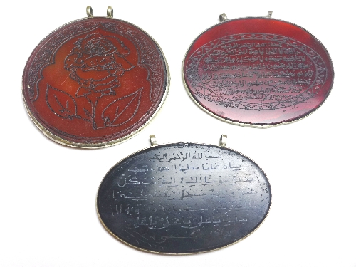 Two C19th Islamic agate pendants, with Koranic verse within white metal mount, the largest 7.5 cm x