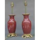 A pair of Song de Beouf Chinese style vases, the rouge glazed bulbous body on a gilt metal