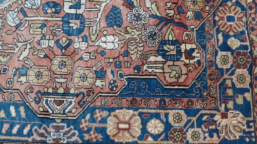 A hand woven Nahavand Persian rug, madder ground with blue floral medallion and border. Width 147 - Image 2 of 3