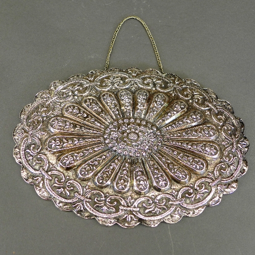 A Turkish mirror, the embossed silver oval shaped back with sunburst floral design, complete with