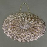 A Turkish mirror, the embossed silver oval shaped back with sunburst floral design, complete with