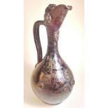 A C19th Turkish pottery ewer, the brown glazed bulbous body and elongated neck with stylized