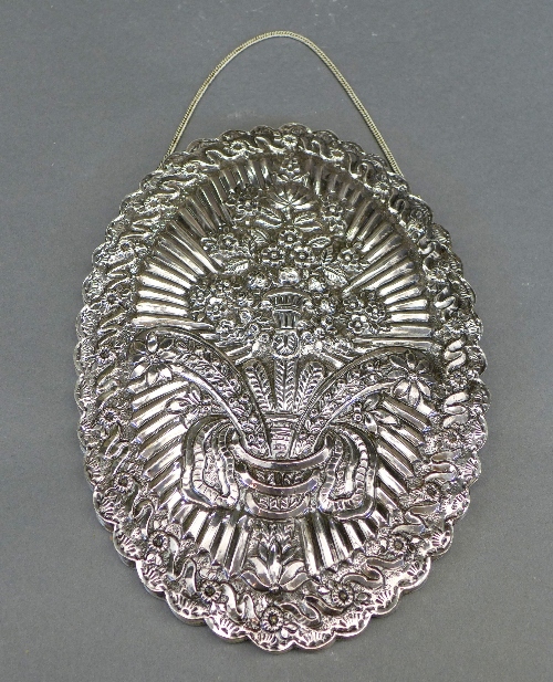 A Turkish white metal mirror, the embossed oval shaped back with central bouquet design within