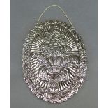 A Turkish white metal mirror, the embossed oval shaped back with central bouquet design within