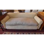 An Edwardian three seater sofa upholstered in beige fabric with cushion seat raised on walnut