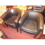 A pair of faux leather armchairs raised on square tapering supports