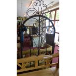A stylized wrought iron garden mirror with arched plate of large size
