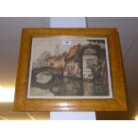 A lithograph of river and bridge scene within maple frame, signed