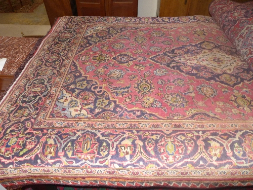 A Kashan rug, the cerise ground with indigo and ivory lobed pole medallion enclosed by similar