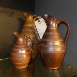 A set of three brown glazed graduated jugs