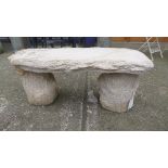 A reconstituted stone garden bench with tree stump form supports