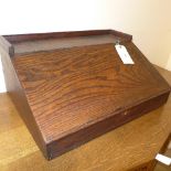 A large wooden sloping fronted table top desk with lift up lid