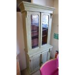 A Victorian green painted bookcase having pair of glazed doors above frieze drawer with cupboard