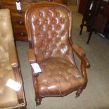 A Victorian mahogany library armchair upholstered in brown button leather having turned supports