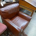 A pair of brown leather armchairs raised on bun feet