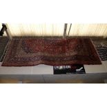 A fine hand knotted rug with floral decoration on blue field within red border