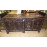 An oak coffer with hinged lid with all over carving and panels