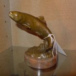 A bronze of a breaching trout on a marbl