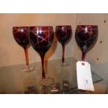 A set of four red glass wine glasses