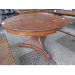 A hardwood circular extending dining table raised on tripod base
