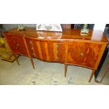 A yewood serpentine sideboard with three single drawers flanked by panel doors raised on reeded