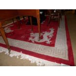 A large Chinese carpet the red field having a pair of entwined dragons to the centre with matching