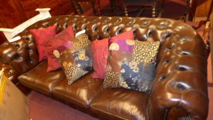 A Chesterfield three seater sofa upholstered in dark brown buttoned leather with brass studded