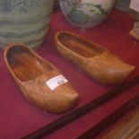 A pair of carved wooden clogs and a Grecian design vase