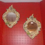 A pair of Italian porcelain rococo style mirrors painted and in floral scrolling frames