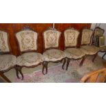 A set of six Louis XV style walnut dining chairs with foliate carved detail upholstered in petit