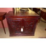 A Chinese rosewood side cabinet, having twin hinged panels to top above carved panel doors enclosing