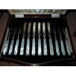 A cased set of silver fruit knives with mother of pearl handles and two silver napkin rings