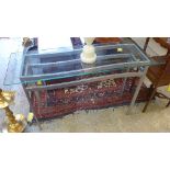 A pair of metal console tables with glass tops