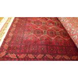 A fine North east Persian Turkoman rug 195 cm x 135 cm repeating gul motifs on a rouge field within