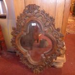 A diamond shaped looking glass within carved stained pine frame