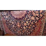 A Keshan style carpet with a floral medallion on a midnight blue field, with red spandrels,
