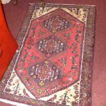 A Persian hand knotted rug the rouge field with three central medallions and geometric motifs in a