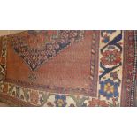 A hand knotted Persian rug the terracotta ground having central pendant within single border