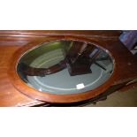 An Edwardian mahogany oval wall mirror with bevelled plate