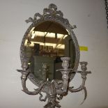 An oval silver gilt wall mirror with triple sconces