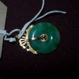 A Chinese 14 carat gold and Apple jade pendant, the pierced jade disc with fan form gold surmount.