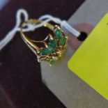 An 18 carat gold, diamond and emerald ring, of floral form being set with three diamonds to the