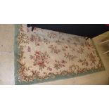 An antique European rug with leaf green border ivory field scattered with roses, 170cm x 24cm.