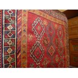 A fine handwoven Persian Shiraz Quasgai runner the madder field with three rows of hooked motifs