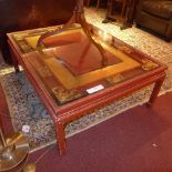 An Oriental red lacquered opium table having carved and gilded detail and plate glass inset top