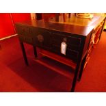 A black lacquered side table of narrow proportions fitted three drawers on square section supports